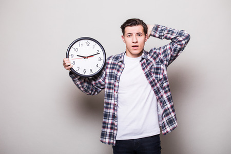 Worried bearded young man in suit with clock in hands miss somethingの写真素材