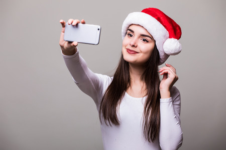 Beautiful female girl model wear santa hat take selfie on phoneの写真素材