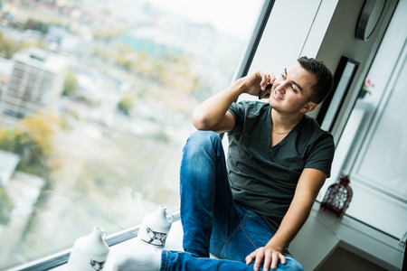 Young man use phone  on panoramic windowの写真素材