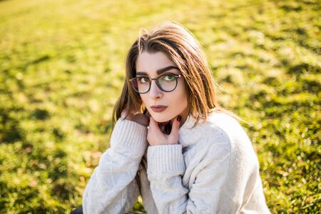 Young Woman sitting on grass in park on sunny dayの写真素材