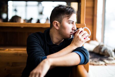 Young man drink  tea in cafe in High Tatry mountainsの写真素材