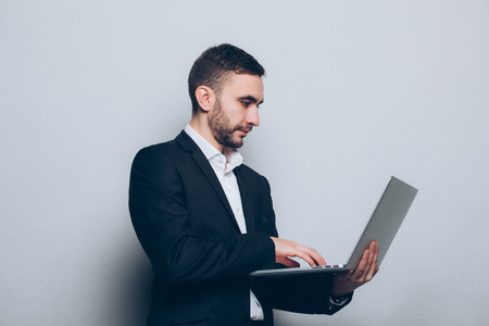 Young businessman in suit with laptop in hands isolatedの写真素材