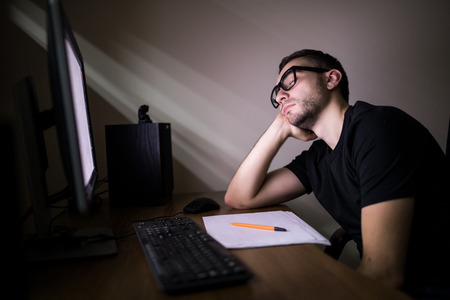 High angle view of tired hacker sleeping near computer at night