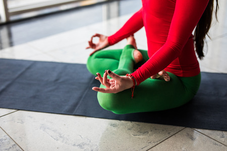 Guptasana. Beautiful yoga woman practice in a big window hall background. Yoga concept.の写真素材