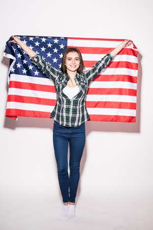 USA patriotism. Young woman with US Flag in hands on white back.の写真素材