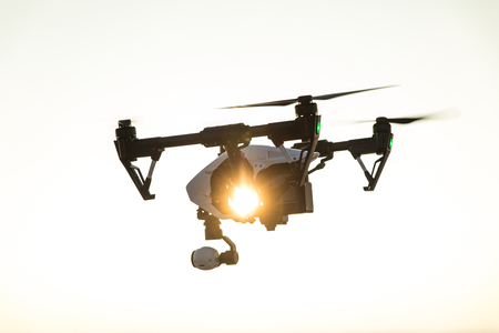 quadrocopter drone with remote control. Dark silhouette against colorfull sunset. Soft focus. Toned imageの写真素材