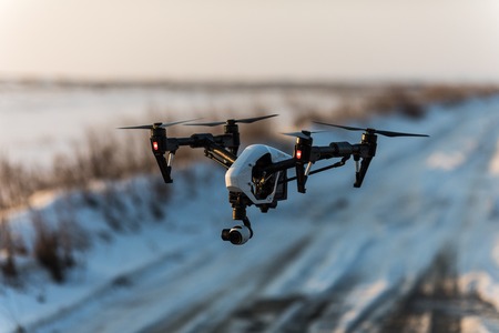 White drone with digital camera flying and landing on snow n winterの写真素材
