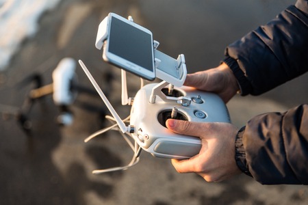 Man with remote control prepare white drone with digital camera for start flying in winter weather with snowの写真素材