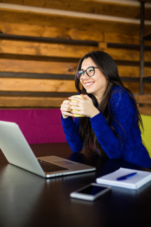 Young lady drink coffee at her working space in modern office. Coworking.の写真素材