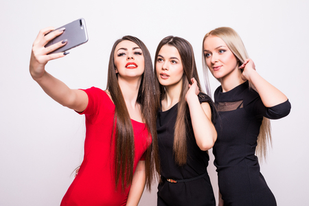 Three models in dresses make selfie on white.の写真素材