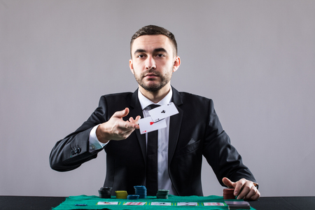 Poker player, on a grey background, throwing two ace cards.
