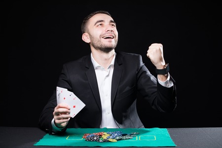 Man with four aces in hands playing on table in casino on black backgroundの写真素材