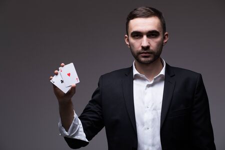 Closeup of man magician with two playing cards in his hand over grey background