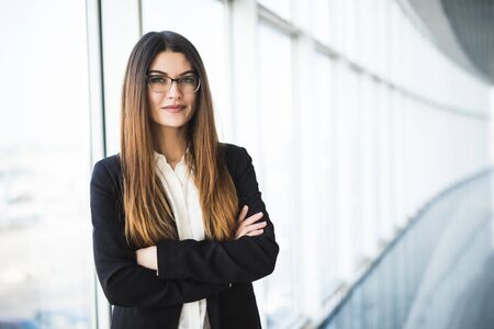 Businesswoman portrait. Businesswoman crossed hands portrait in office with panormic windows.