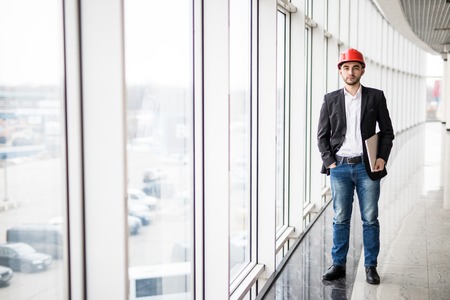 Portrait of elegant engineer in hardhat with laptop computer, smiling at camera.