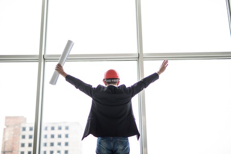 Satisfied architect with celebration gesture against panoramic window