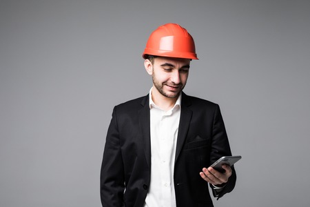 Portrait of happy male engineer using mobile phone on white background