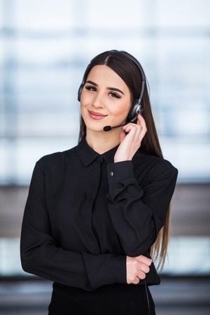 Portrait of happy smiling female customer support phone operator at workplace.の写真素材