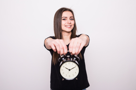 Happy woman holding clock against a grey backgroundの写真素材