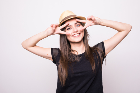 Cheerful girl in cap making faces on camera on grey backの写真素材