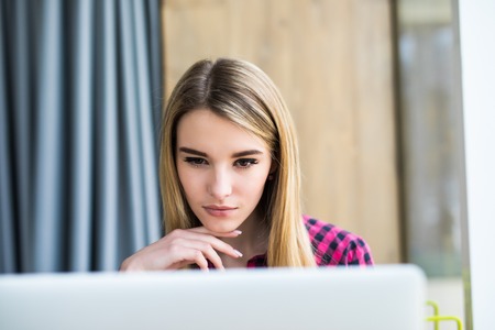 Portrait of happy young beauty woman using laptop at office table or cafe. Indoorsの写真素材