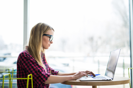 young woman worker sitting in office while using laptop computer and typing by keyboardの写真素材
