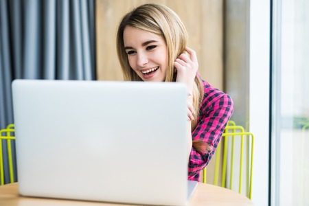 Woman smile while looking at laptop in office. indoorsの写真素材