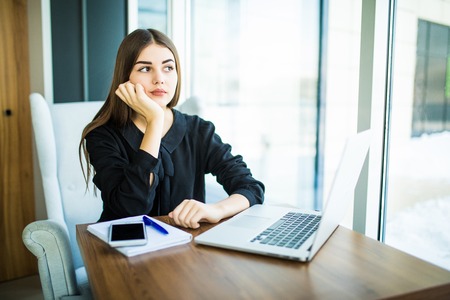 Beautiful brunette using notebook in cafe near windowの写真素材