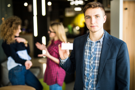 Young man pointed white screen in front of his girls coworkers in modern office.の写真素材