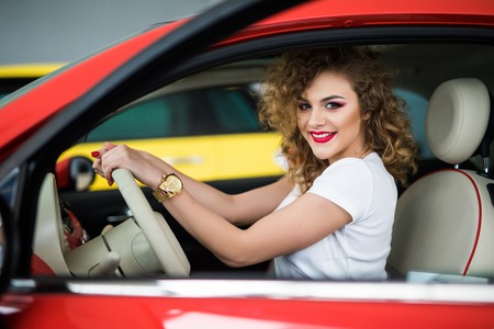 Pretty young woman driving her new car and look at camera from windowの写真素材