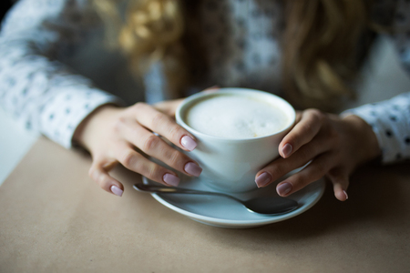Close up image of woman hands shaking cappuccino at shabby chic table. Morning mood.の写真素材