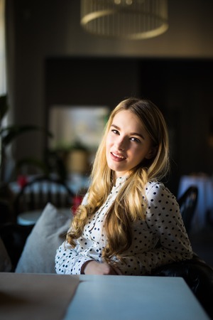 Beautiful young woman with a cup of tea at a cafeの写真素材