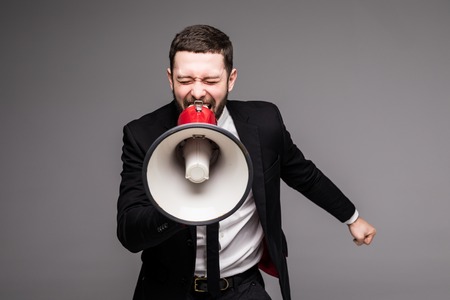 Business man screaming with a megaphone on grey backgroundの写真素材
