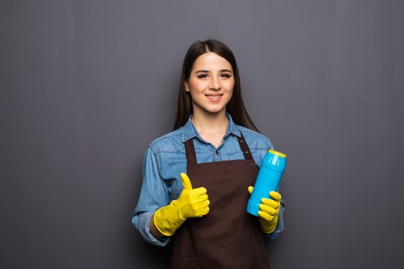 Smiling woman holding bottle of chemistry for cleaning house. Isolated portrait.の写真素材
