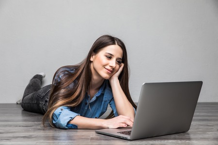Smiling Woman Working on Laptop on Floor in roomの写真素材
