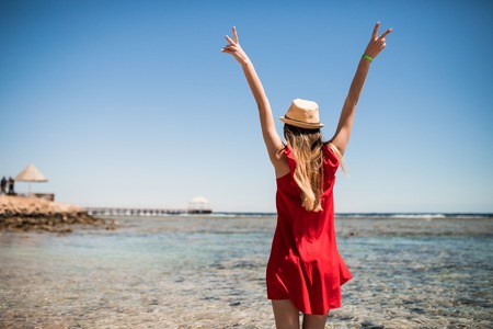 Woman enjoying freedom on a ocean shore with hands raisedの写真素材