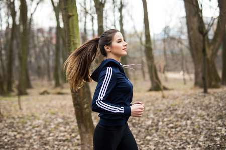 Young woman running outdoors in a city park on early spring dayの写真素材