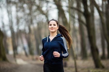 Young woman running and training in autumn natureの写真素材