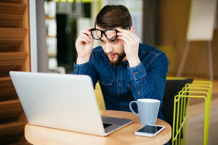 Business man with glasses having eyesight problems confused with laptop isolated on gray background. Vision related changes. Human face expressionの写真素材