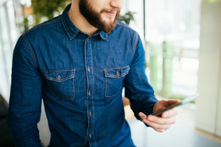 Portrait of man with mobile phone in cafeの写真素材