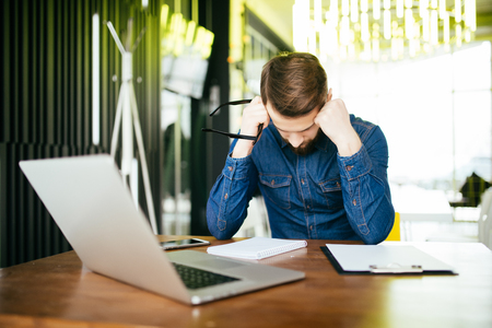 Worried businessman lamenting in front of a computer at officeの写真素材
