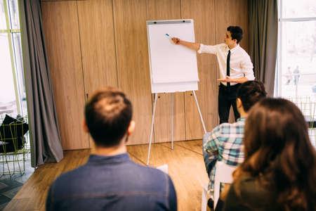 Confident young businessman giving presentation using flipchart in officeの写真素材