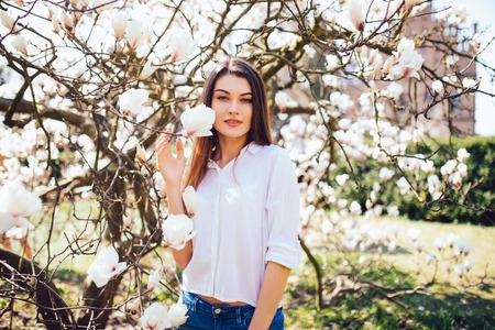Beauty woman standing on background Magnolia blossoming flowers.の写真素材