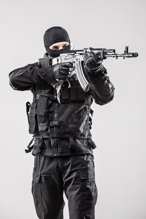 Terrorism concept: Terrorist holding a machine gun in his hands isolated over whiteの写真素材