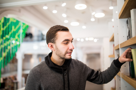 Male student picking a book in a libraryの写真素材