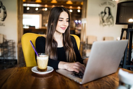 outdoor portrait of a young girl she works as a freelancer in a cafe drinking a delicious hot Cup of coffee from text send mailの写真素材