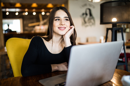 Beautiful attractive woman at the cafe with a laptop dreamingの写真素材