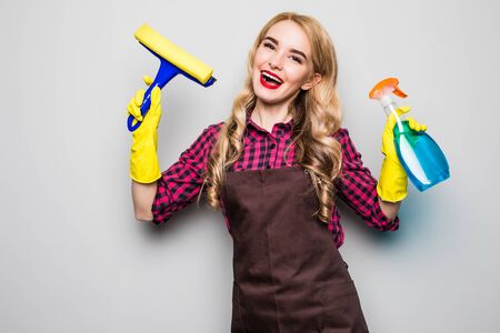 Happy young woman cleaning windows isolated on greyの写真素材
