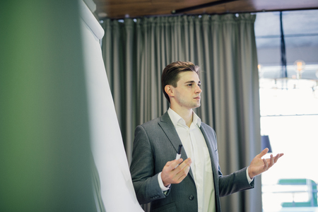 Confident team leader or manager standing in front of a flip chart and present project on officeの写真素材