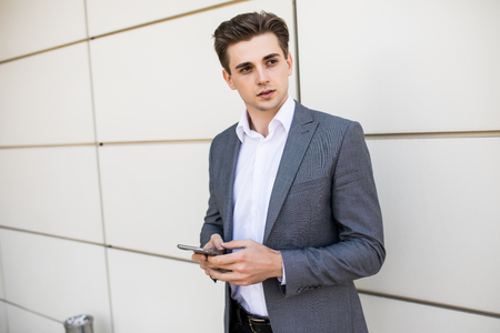Young urban professional man using smart phone in office building indoors.の写真素材